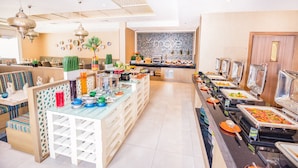 Een buffetgedeelte met diverse thematafels, een zithoek met comfortabele banken en een wand met een mozaïekpatroon.