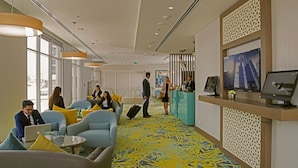Een hotellobby met zitgedeeltes, een receptiebalie en een groot raam.
