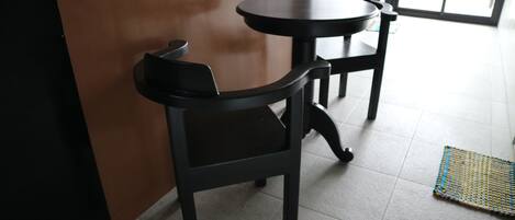 A room with two black tables and chairs, a brown wall, and a tiled floor.