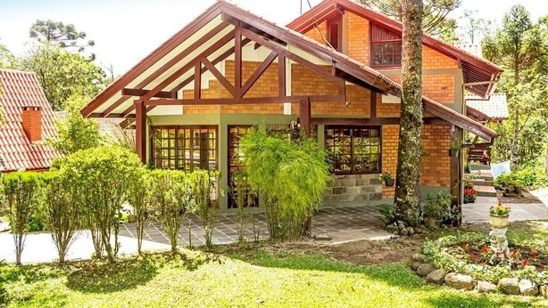 A two-story house with a sloped roof, wooden beams, and a brick exterior.