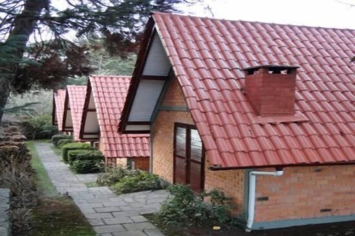 A row of small, brick houses with red-tiled roofs and a narrow pathway between them.