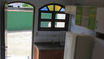Uma cozinha compacta com pia embutida, armários de madeira e janela com moldura verde.