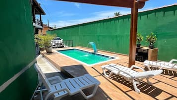 Una piscina al aire libre, sillones reclinables de piscina