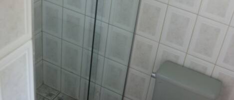 A bathroom with tiled walls, a glass shower enclosure, and a toilet.