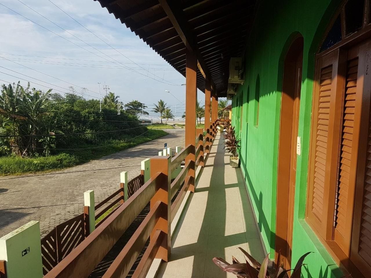 Un edificio con fachada verde y un corredor cubierto.