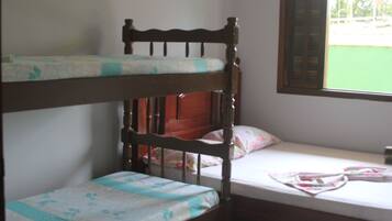 A bunk bed with a wooden headboard, a lower bunk with a floral bedspread, and a single bed with a pink floral bedspread.