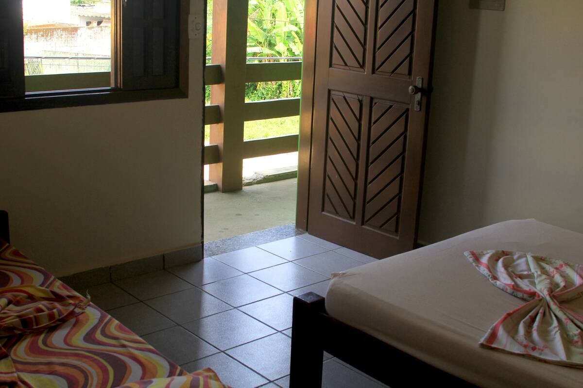 Ein Zimmer mit einem Bett, einem Fenster und einer Tür, die nach draußen führt.