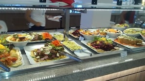 A buffet with various dishes, including salads, meats, and desserts, displayed in a glass case. - Diroma Lacqua I - Direto com o Grupo Diroma - Acesso ao Acqua Park com Café da Manhã (Caldas Novas)