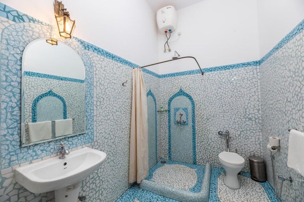 Un baño con lavamanos, inodoro, ducha y mosaicos decorativos.