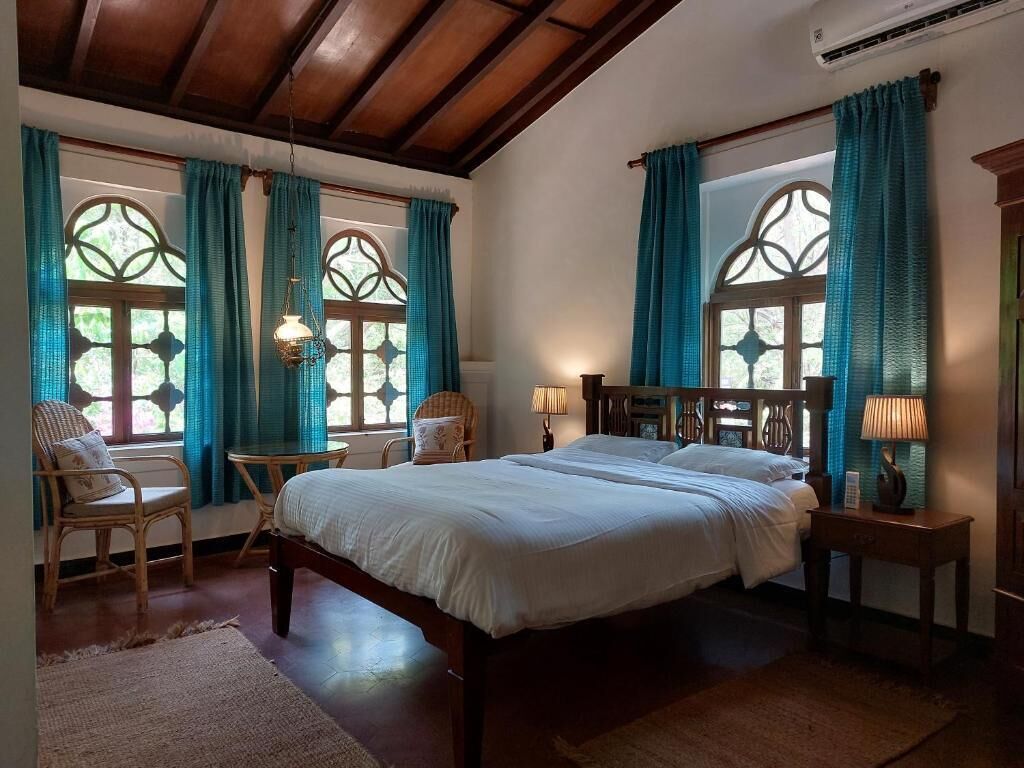 Un dormitorio con una cama grande, dos mesitas de noche, una silla y una ventana con cortinas.