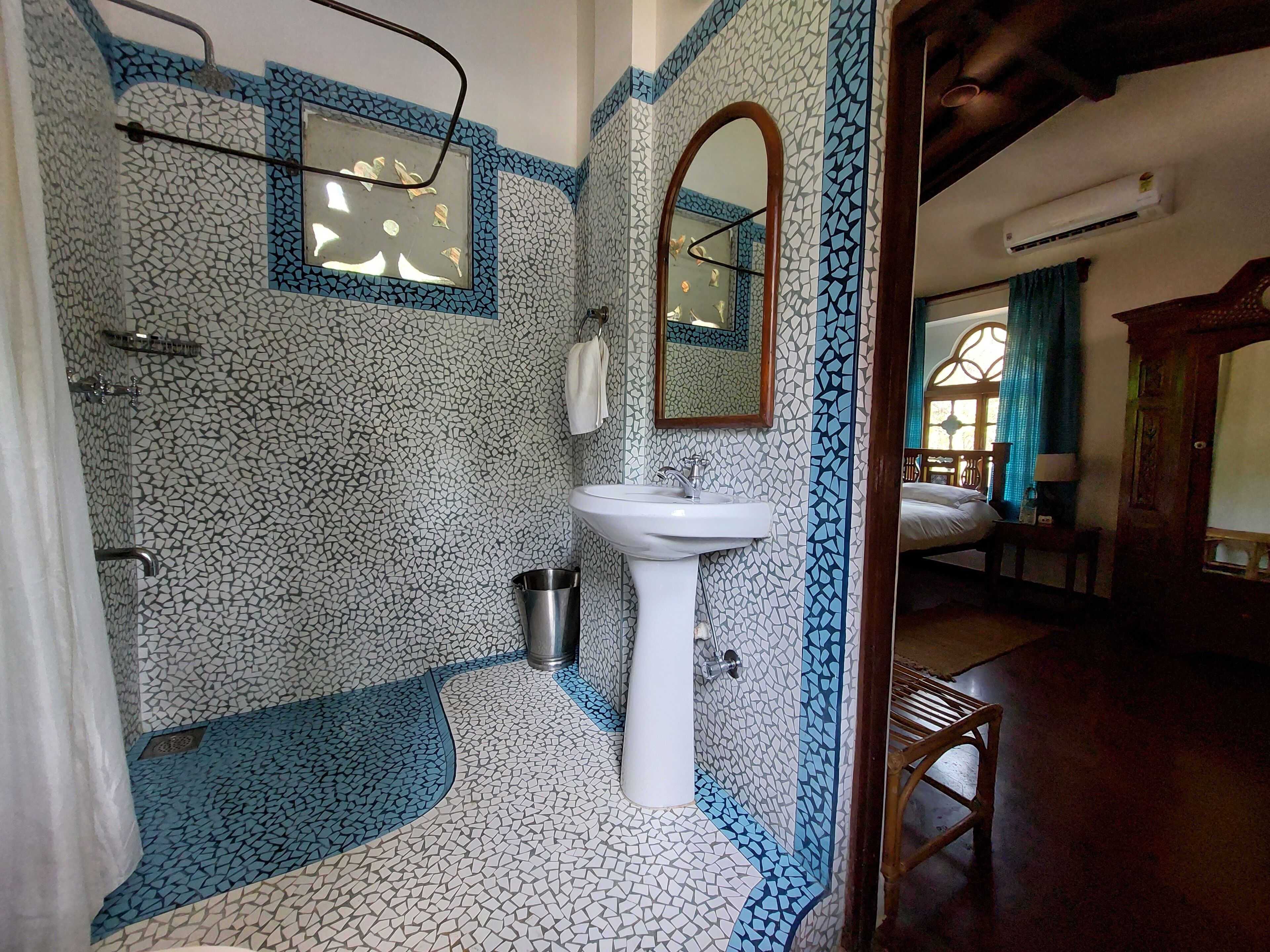 A bathroom with mosaic tile walls, a sink, and a shower.