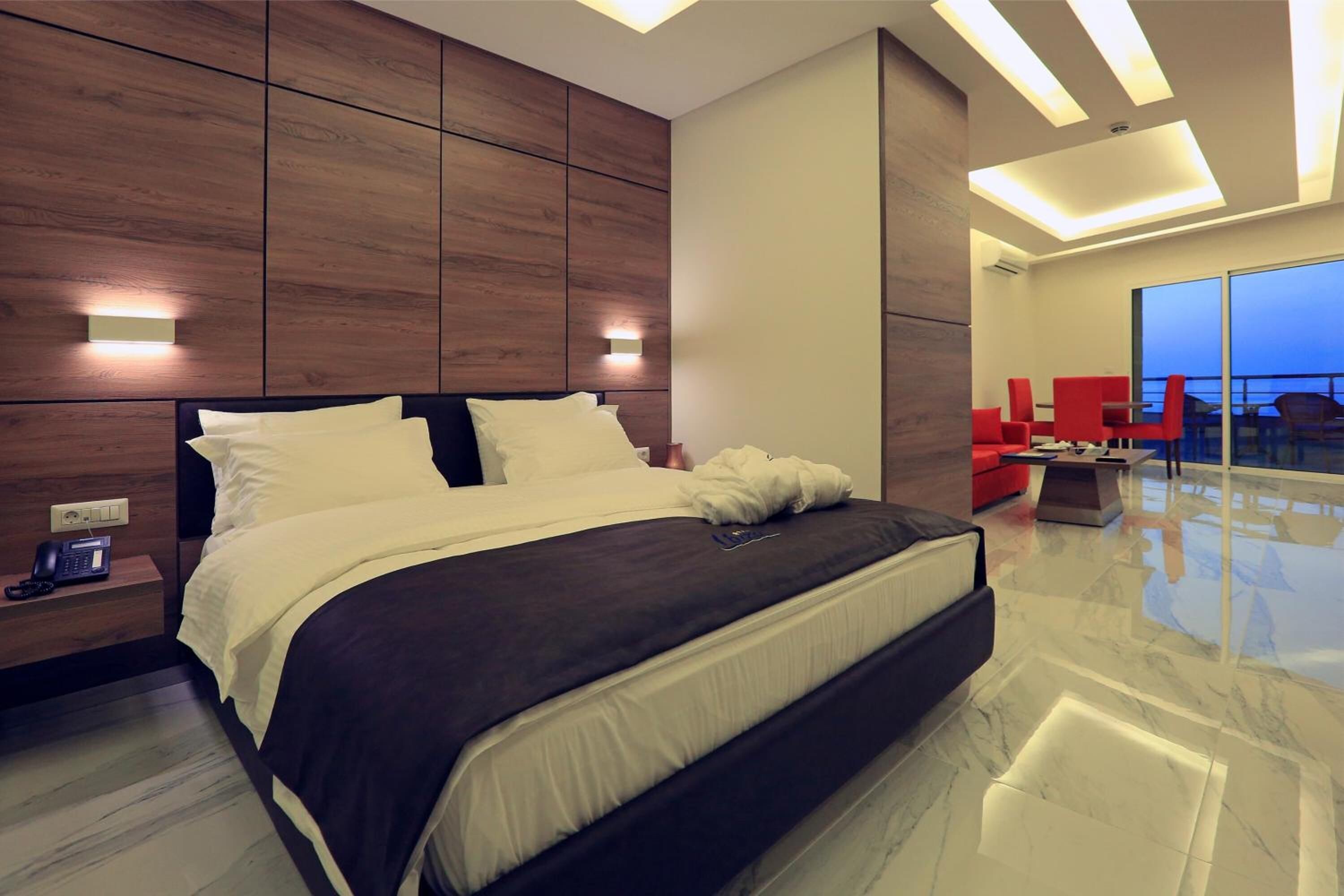 A modern bedroom with a large bed, bedside tables, and a view of the city through large windows.