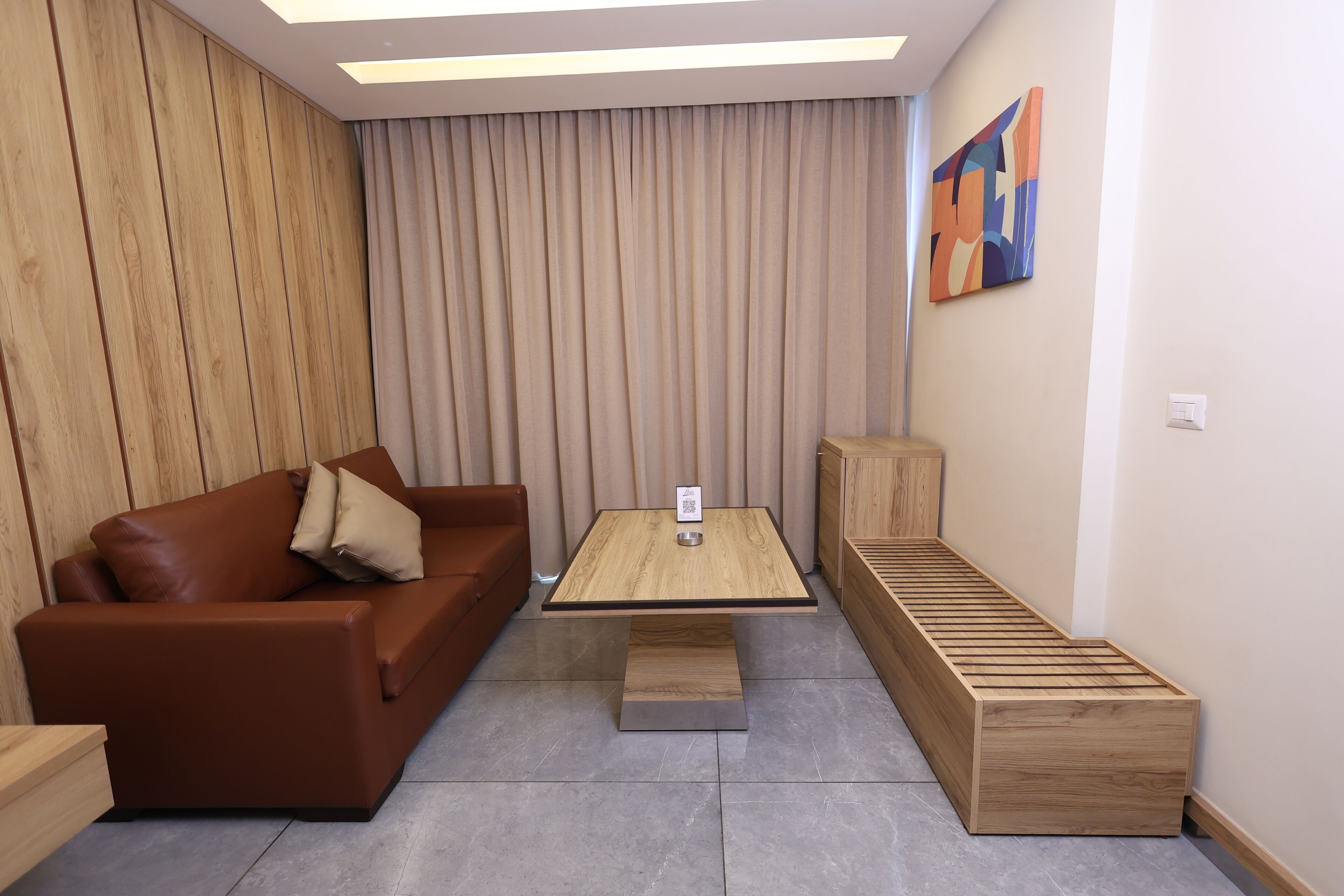 A modern living room with a brown leather sofa, a wooden coffee table, and a bench.
