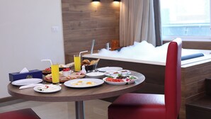 A breakfast table with plates of food, a juice glass, and a basket of bread.