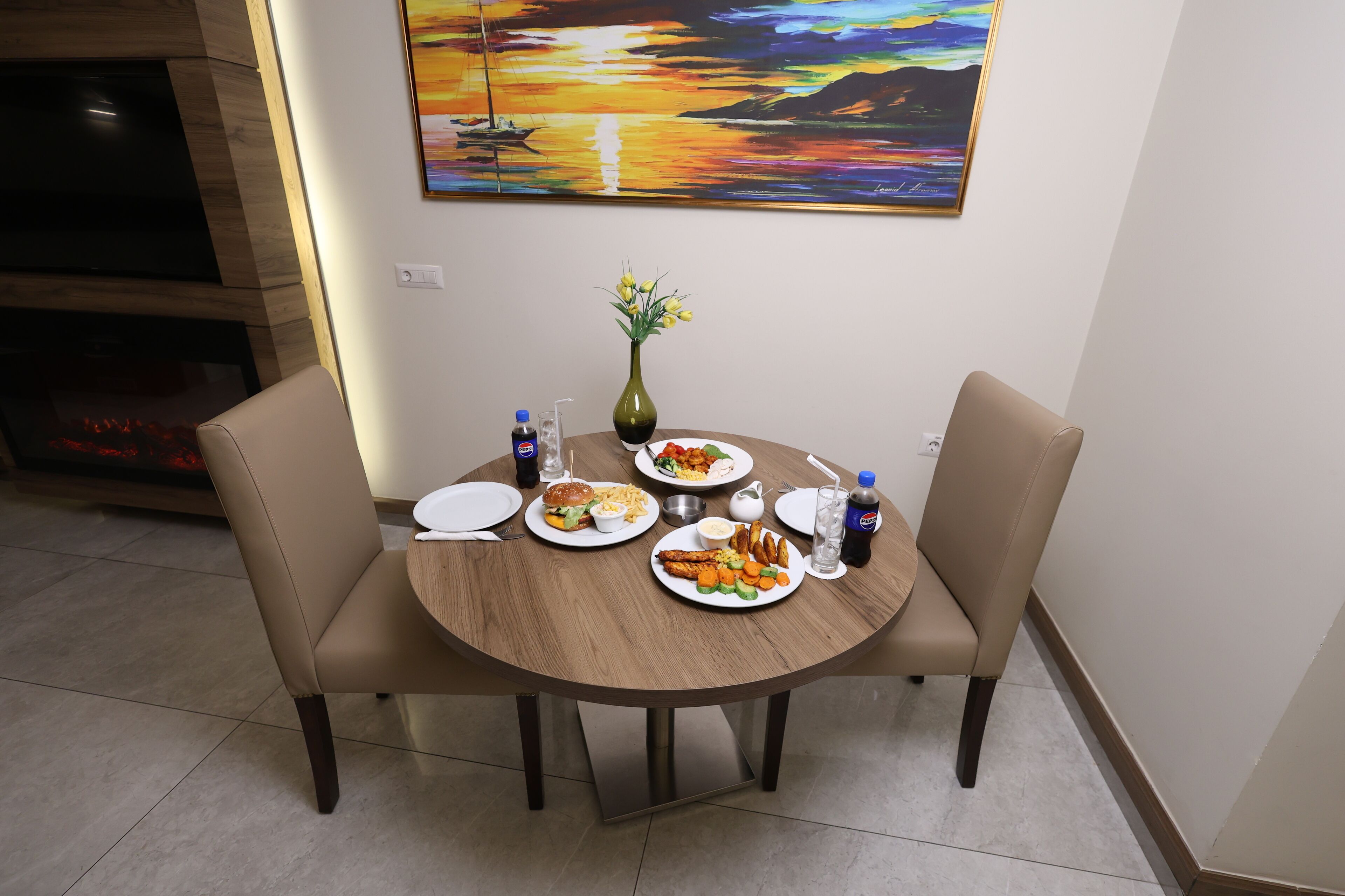 A dining table with four chairs, a vase with flowers, and plates of food.