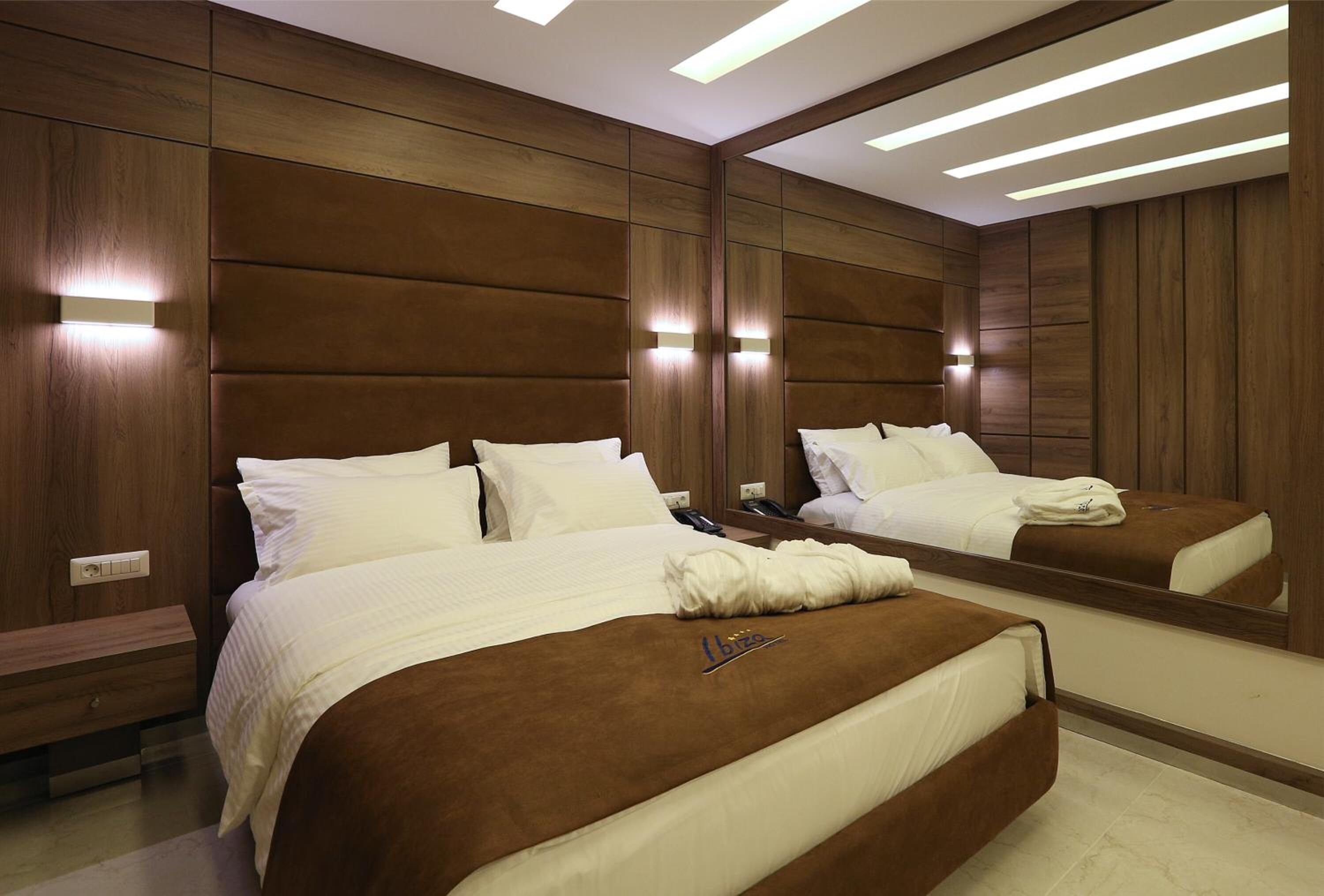 A hotel room with two beds, wooden paneling, and built-in lighting.