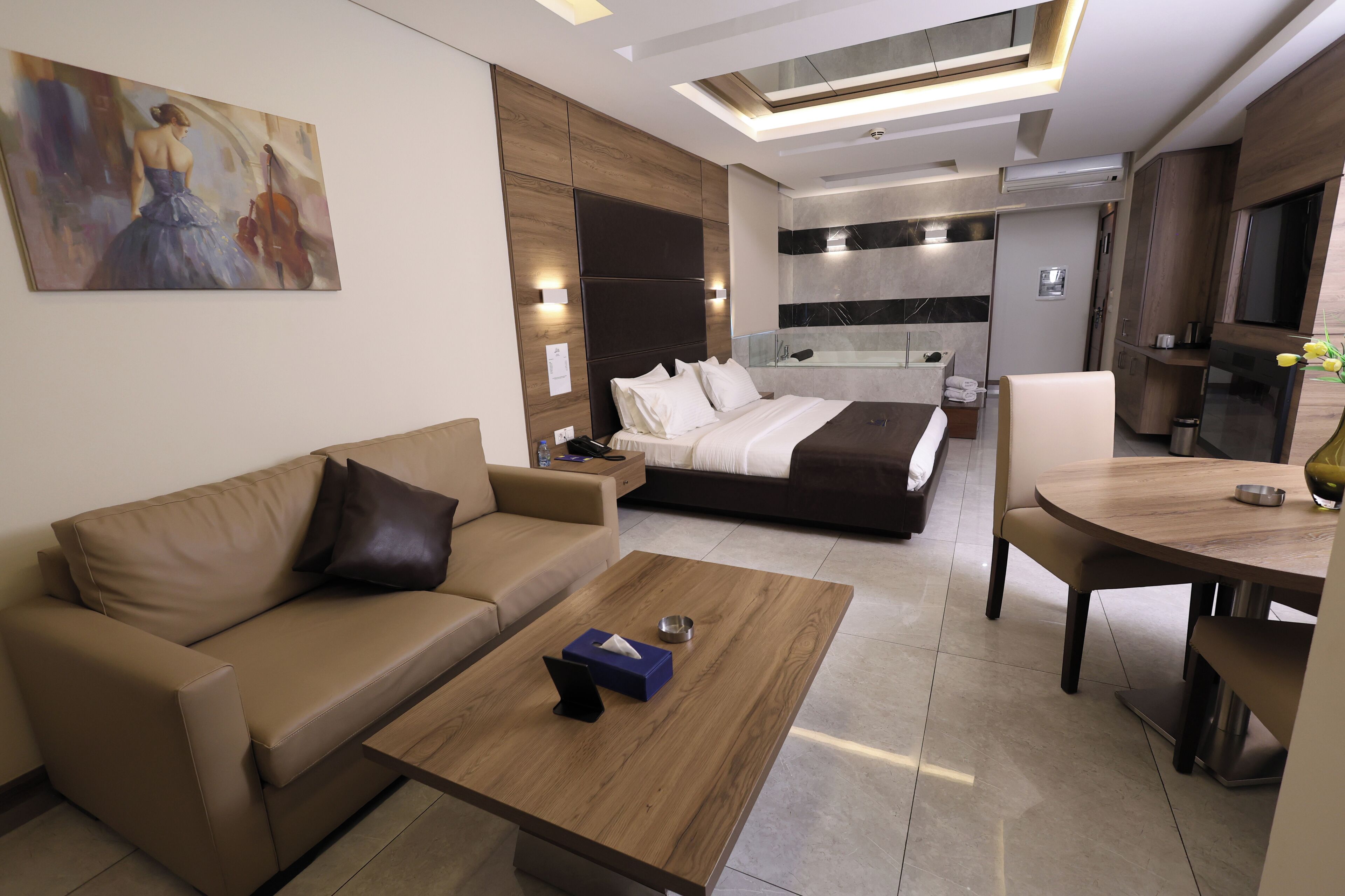 Une chambre d’hôtel moderne avec un canapé, un lit, une table à manger et un tableau au mur.