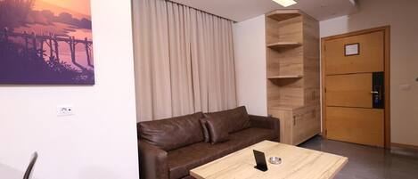 Uma sala de estar moderna com um sofá de couro marrom, uma mesa de centro de madeira e um quadro com um pôr do sol na parede.