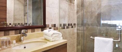 A modern bathroom with a glass-enclosed shower, a vanity with a mirror, and a sink.