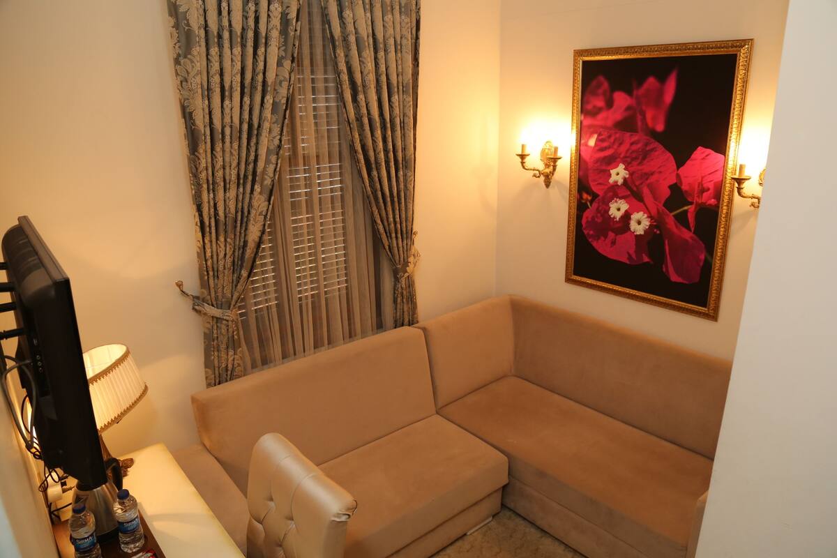 A living room with a beige sofa, a lamp, a television, and a wall-mounted picture frame.