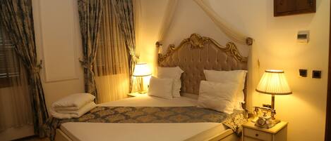 A neatly made bed with a canopy, two bedside lamps, and a nightstand with a clock.