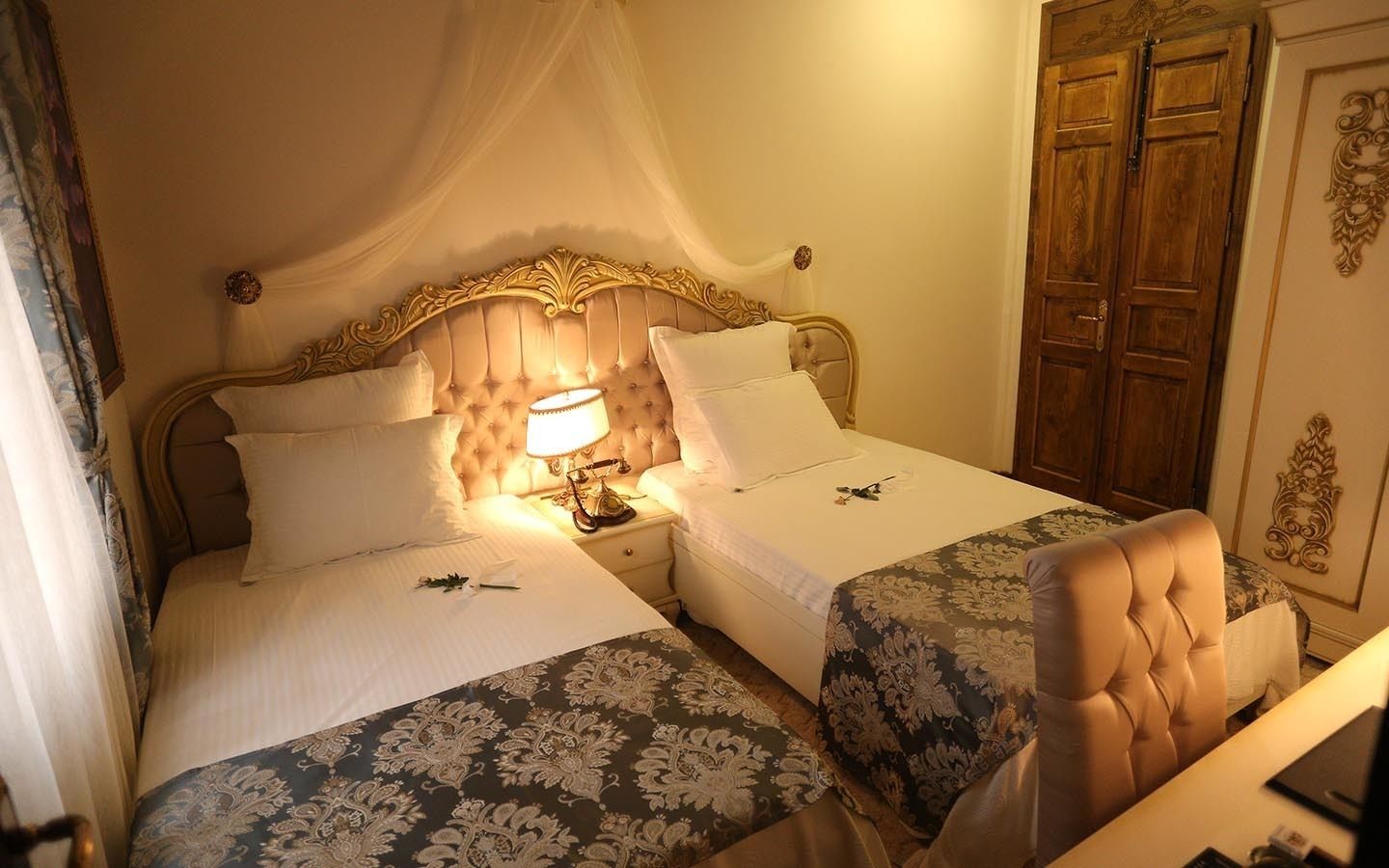 Una cama doble con dosel, dos mesitas de noche y una mesilla con lámpara.