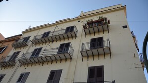 A multi-story building with balconies, some with plants. - Appartamento Cavour 37 Palermo (Palermo)