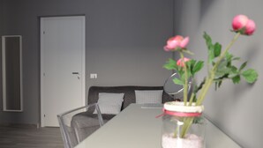 A modern living room with a white sofa, a glass coffee table, and a vase with pink flowers. - Appartamento Cavour 37 Palermo (Palermo)