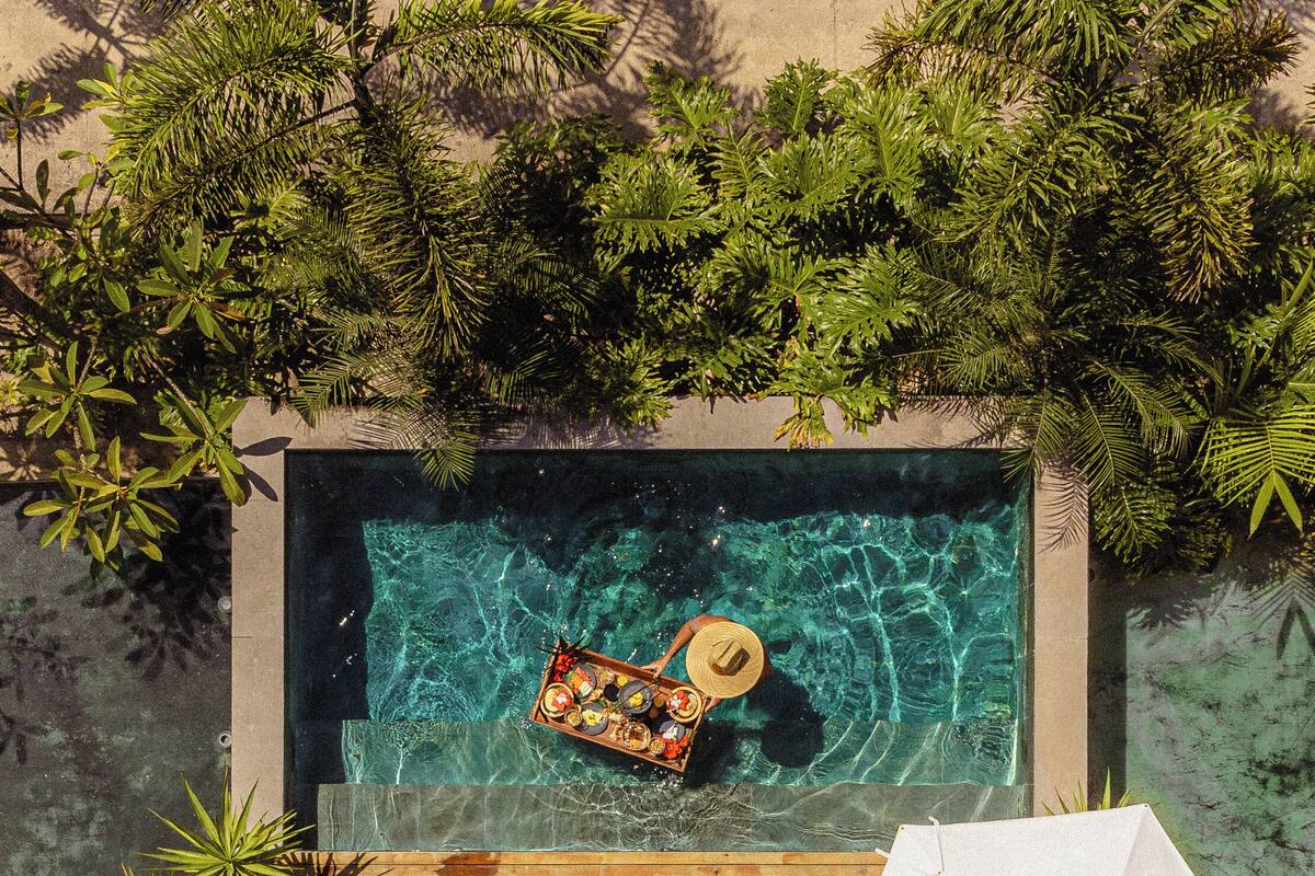 A wooden deck with a pool, lounge chairs, and an umbrella.