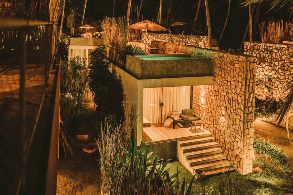 A modern villa with a stone exterior, a small pool, and a patio area with outdoor furniture.