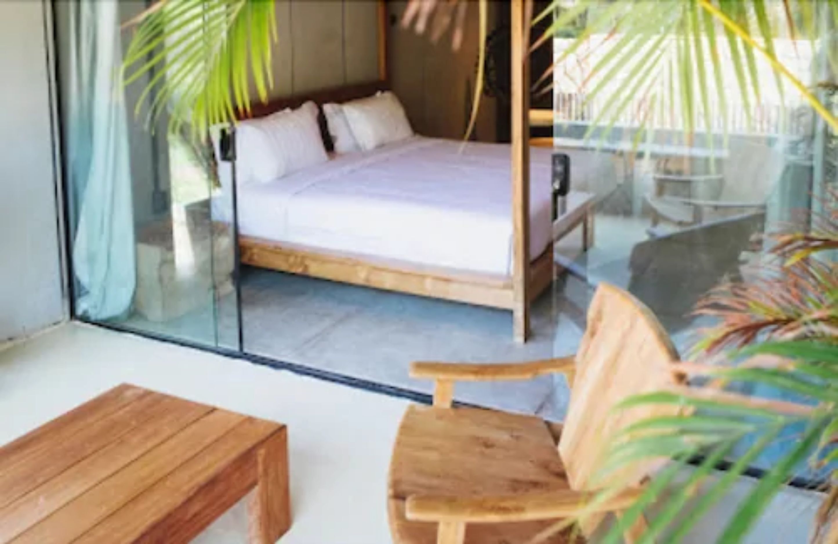 A bedroom with a bed, a wooden chair, and a glass partition.