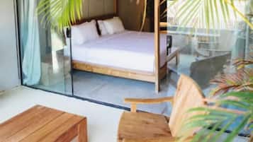 Un dormitorio con cama, una silla de madera y un separador de vidrio.
