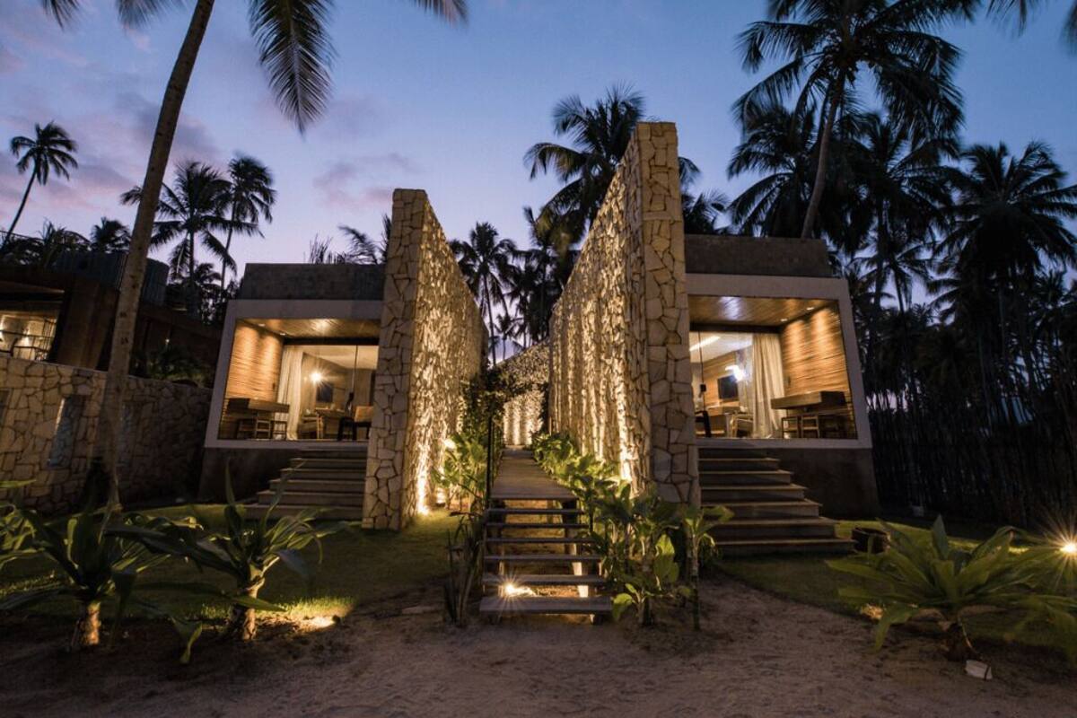 A modern villa with a stone facade, a central staircase, and a well-lit interior.