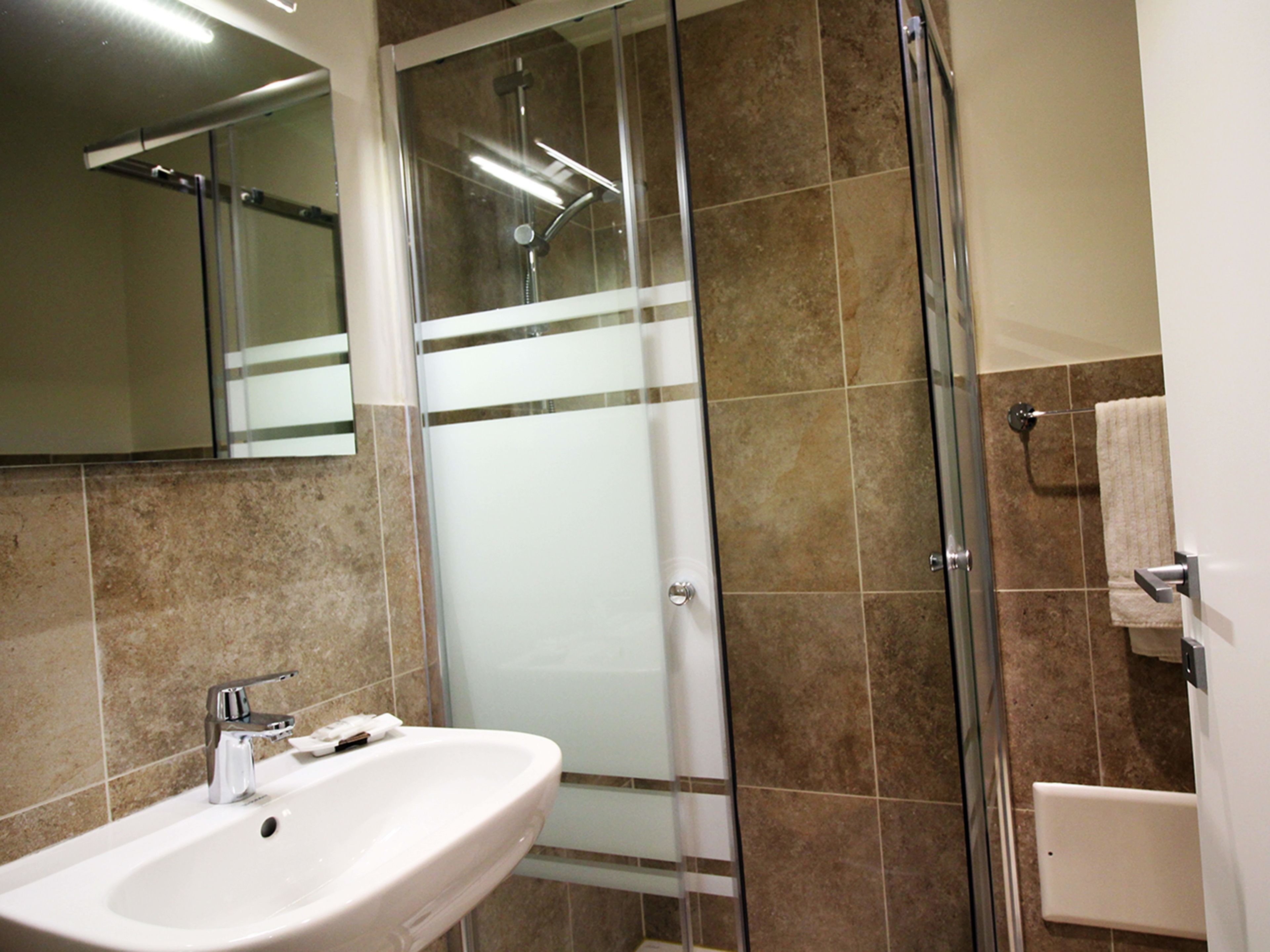 A bathroom with a sink, a glass shower enclosure, and a towel rack.