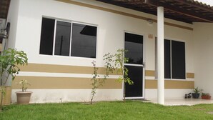 A building with a white and beige facade, large windows, and a covered porch area. - Casa póxima ao Aeroporto e UFAL (Maceió)