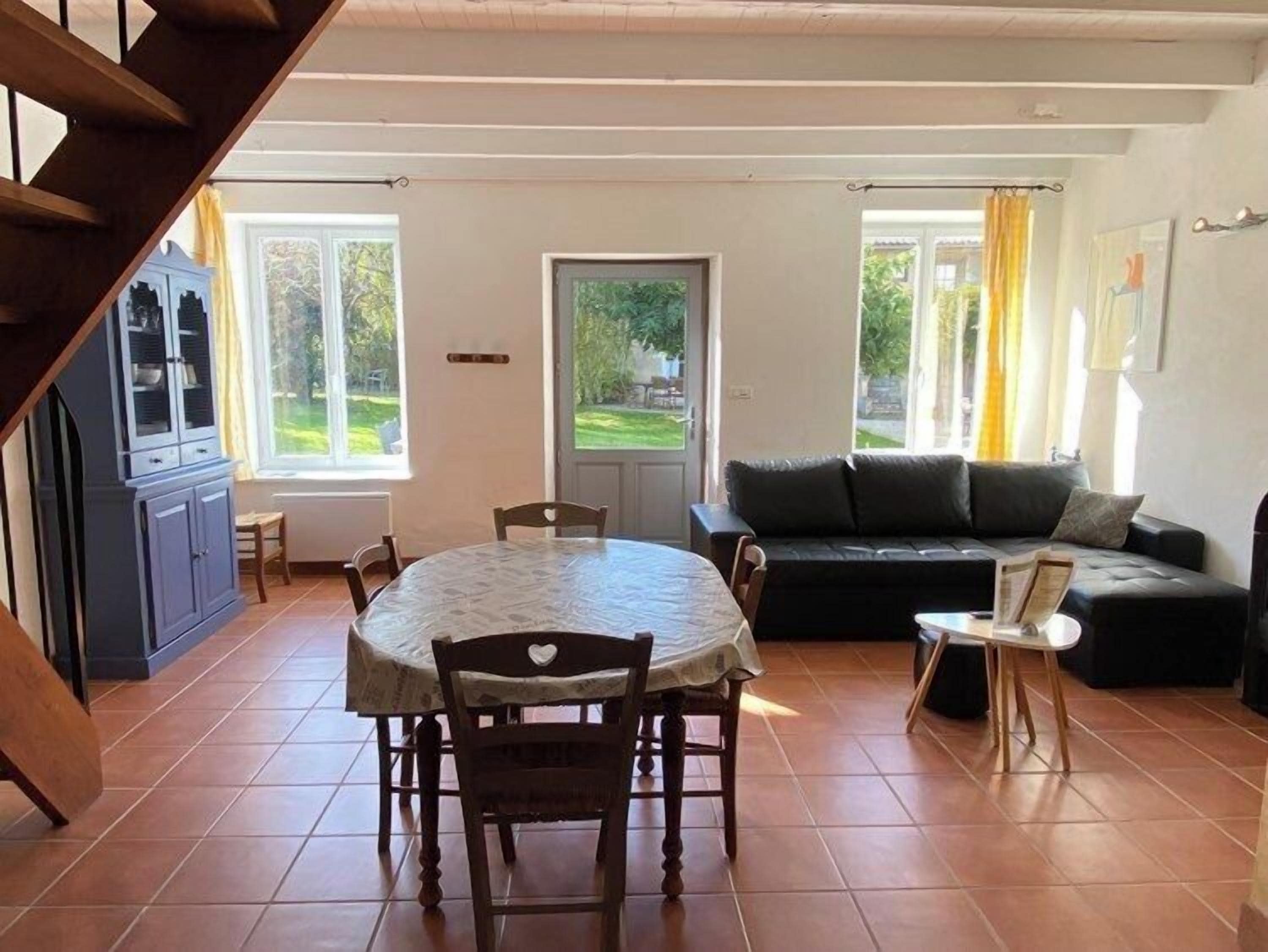 A spacious living area with a dining table, sofa, and a staircase.