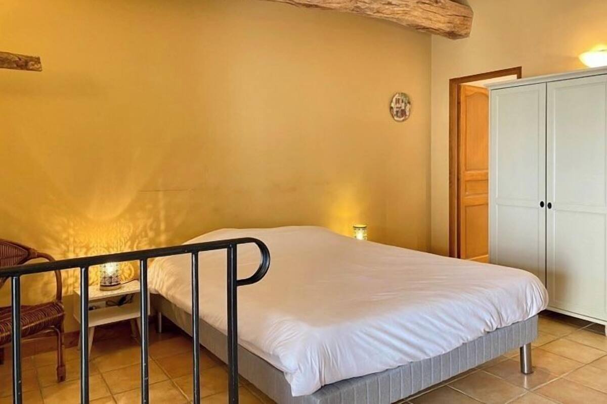 Ein Schlafzimmer mit einem Bett, einem hölzernen Stuhl, einem Kleiderschrank und einem Deckenbalken.
