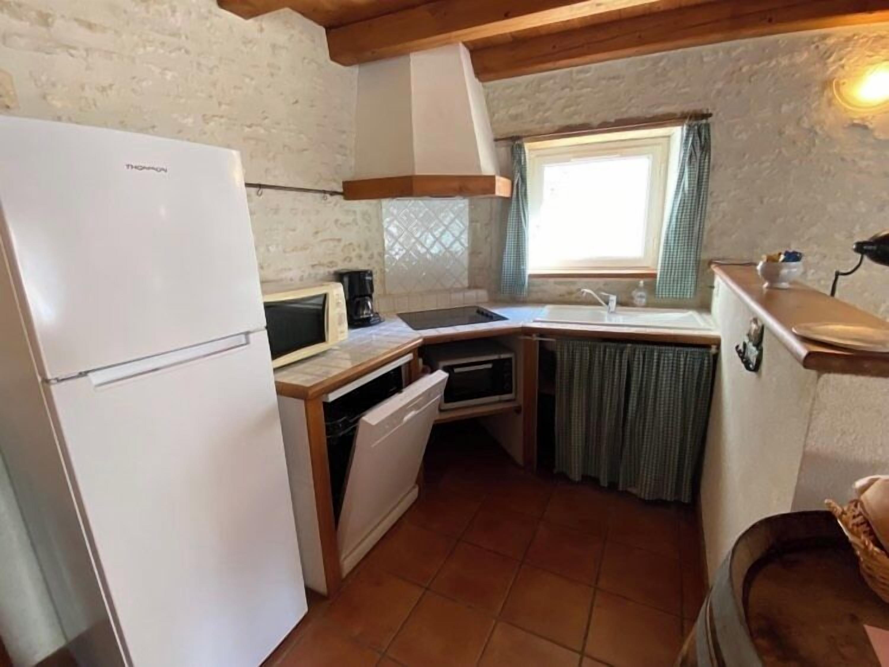 Cocina compacta con un refrigerador blanco, microondas, pileta y horno pequeño.
