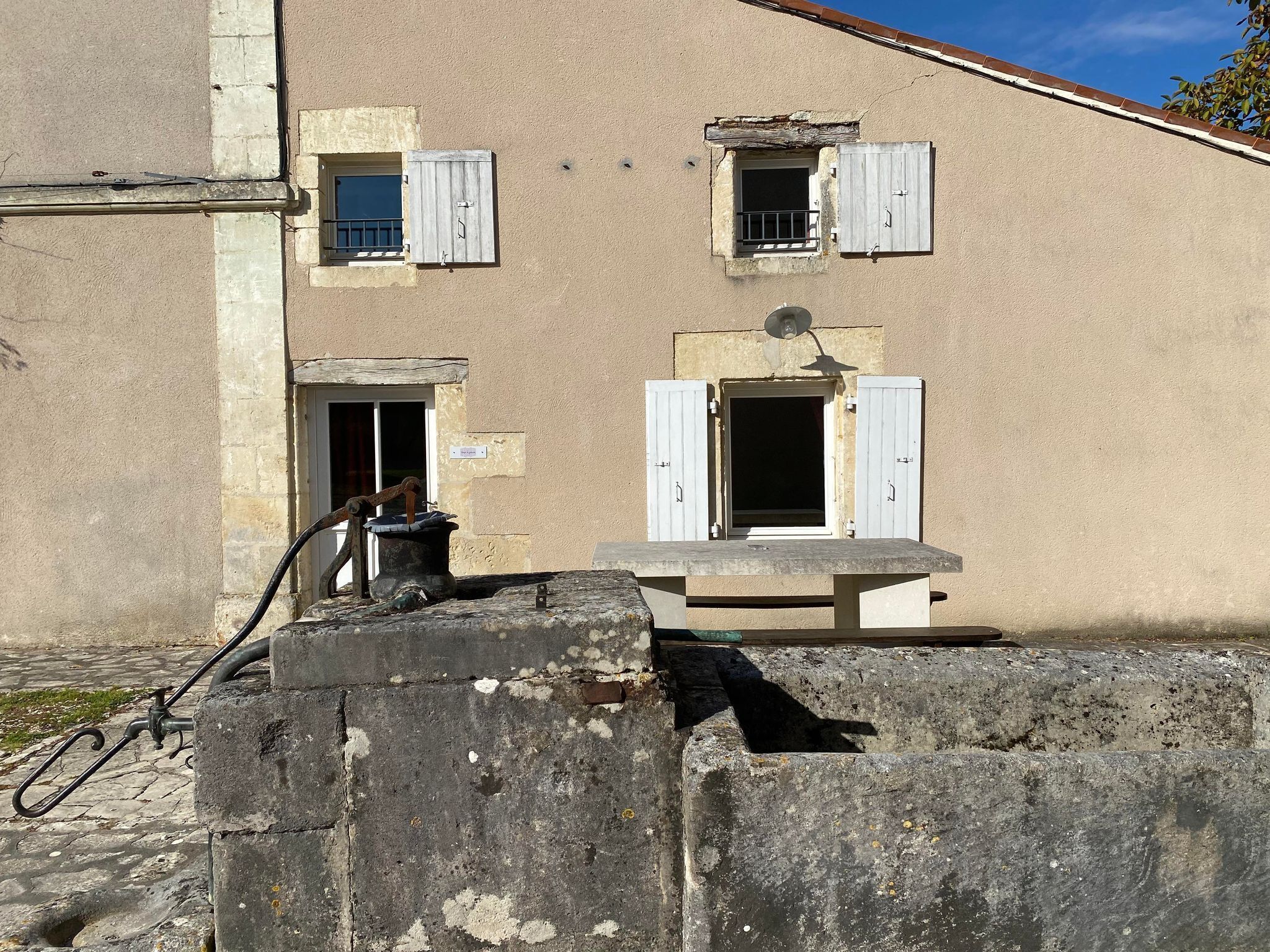 Un edificio con varias ventanas, algunas con contraventanas, y una estructura de hormigón al frente.
