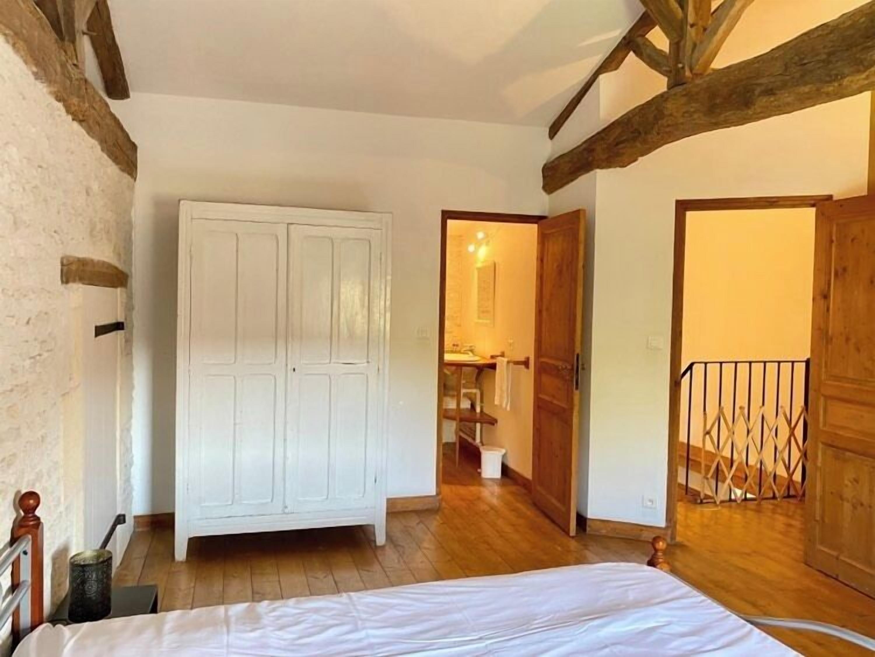 A bedroom with a wooden wardrobe, a bed, and a wooden floor.