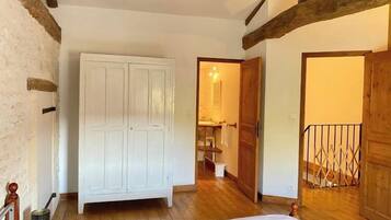 A bedroom with a wooden wardrobe, a bed, and a wooden floor.