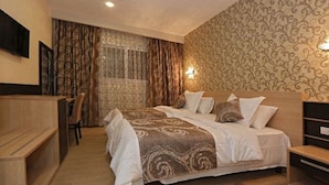 A hotel room with a large bed, a wooden desk, and a chair. - Hôtel Saray (Algiers)