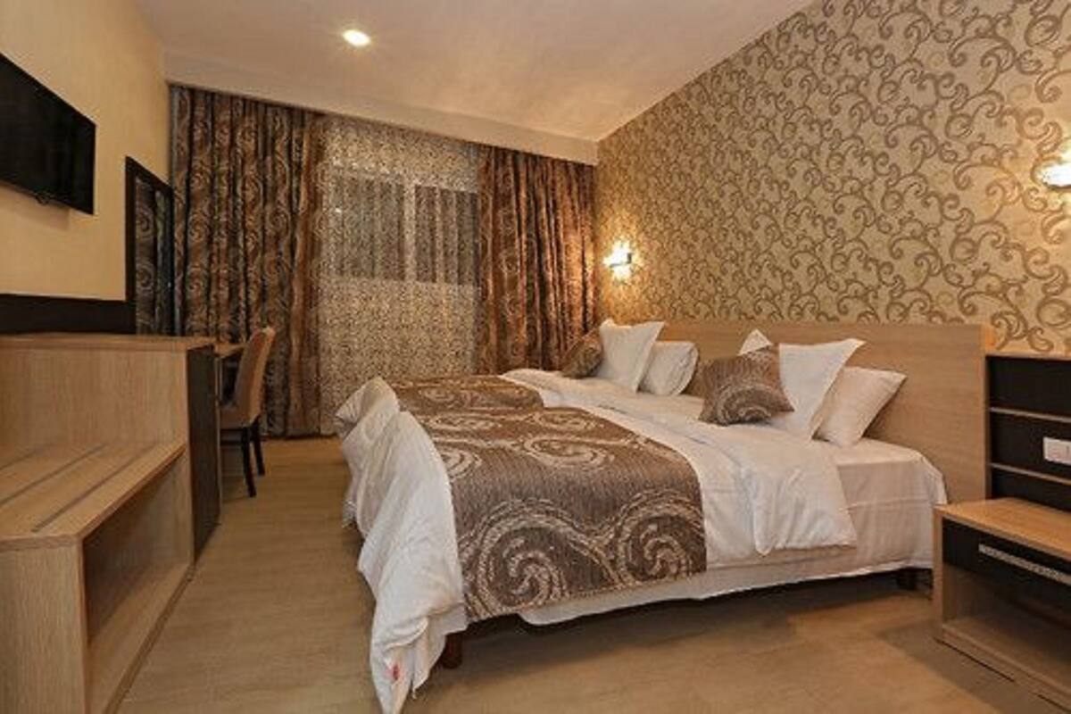 A hotel room with a large bed, a wooden desk, and a chair.