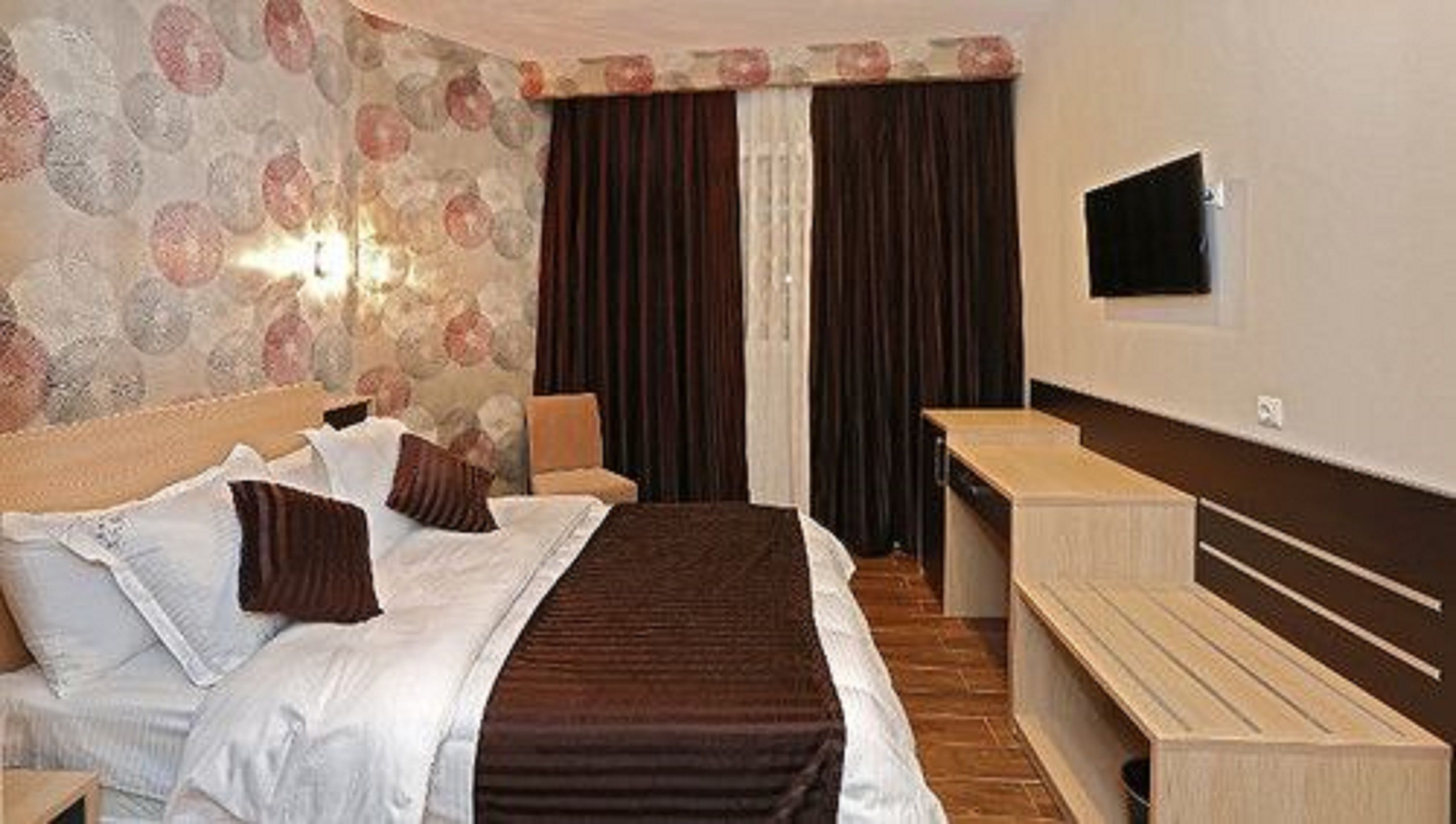 Una habitació d'hotel amb un llit, un escriptori i una televisió.