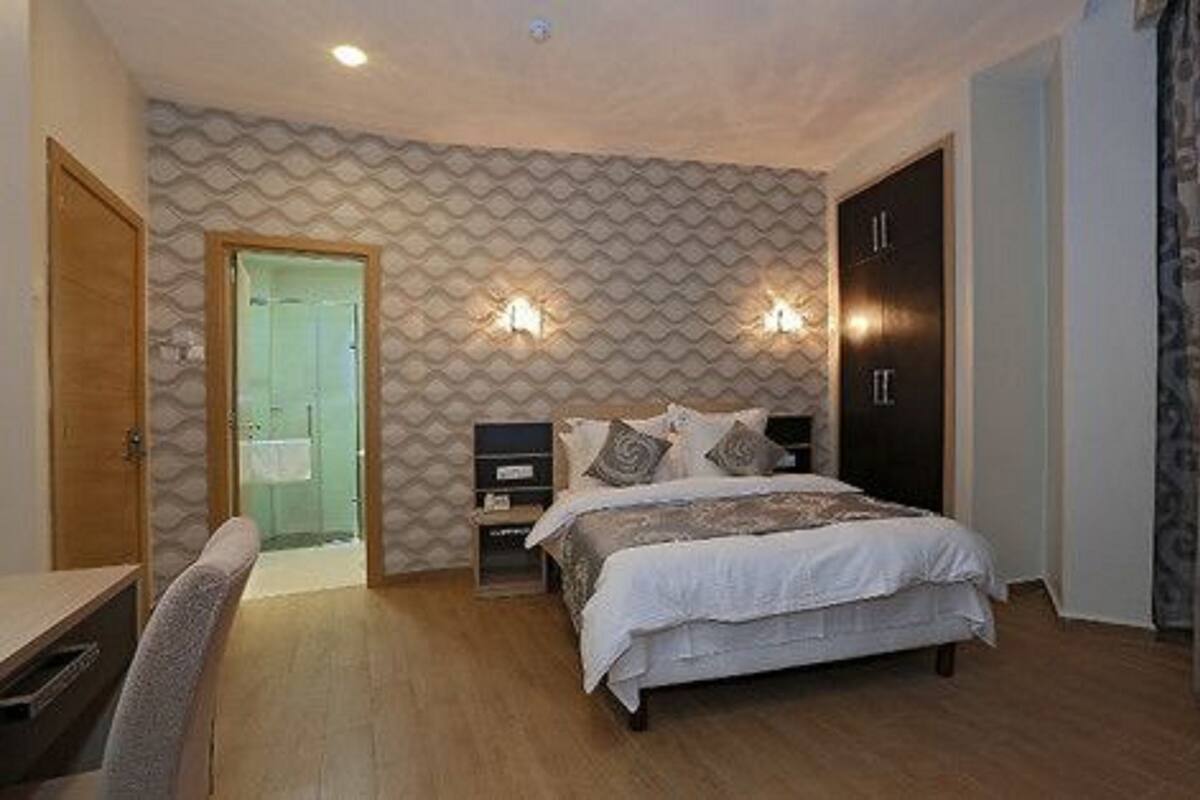 A bedroom with a bed, nightstands, a desk, and a wardrobe.