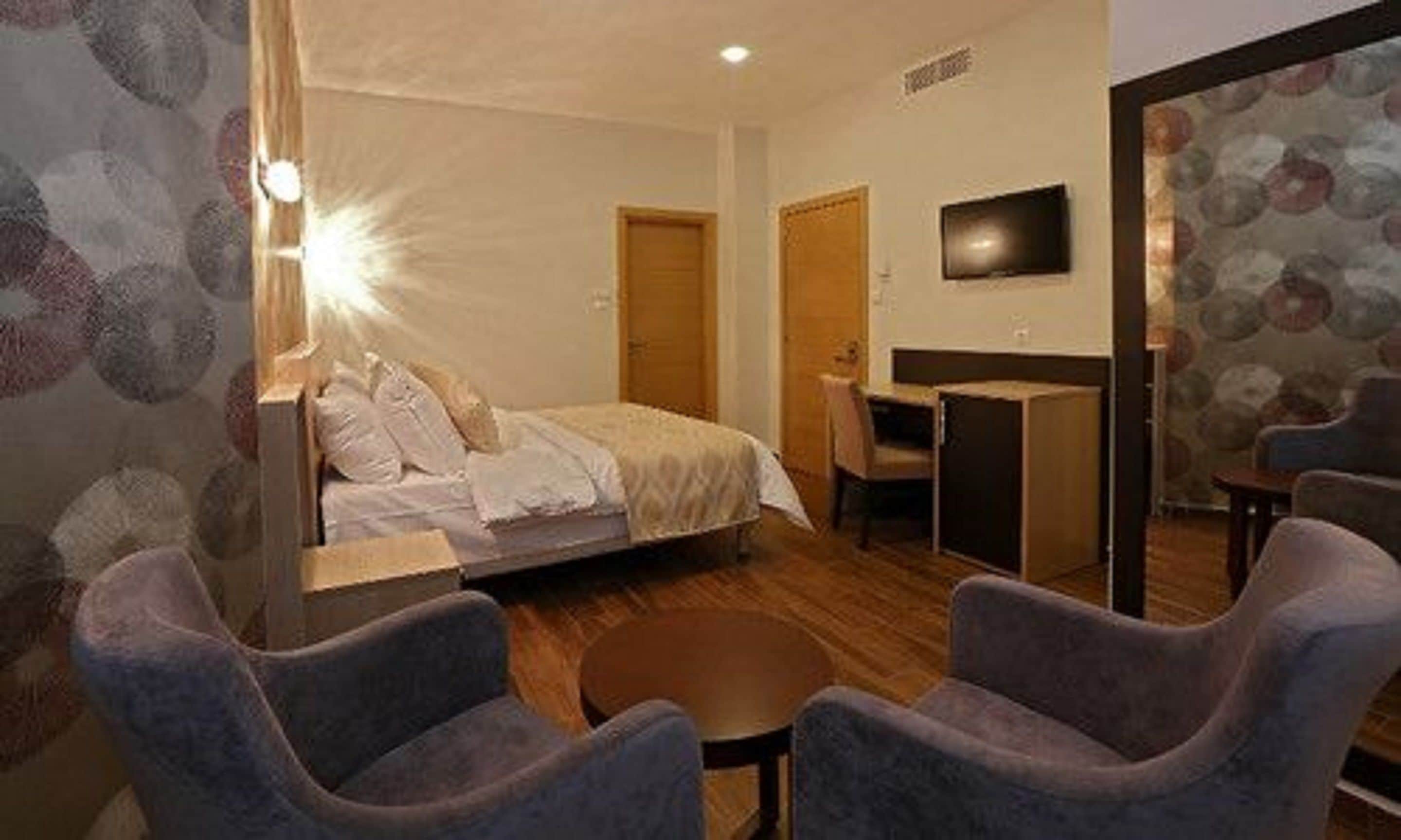 Una habitación de hotel con cama, escritorio, silla y televisor.