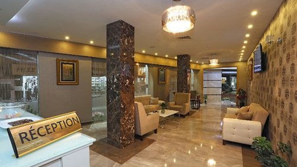 A reception area with a marble column, a reception desk, and seating arrangements. - Hôtel Saray (Algiers)