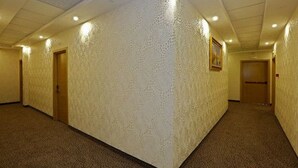 A hotel corridor with textured walls, carpeted floors, and doors leading to rooms. - Hôtel Saray (Algiers)