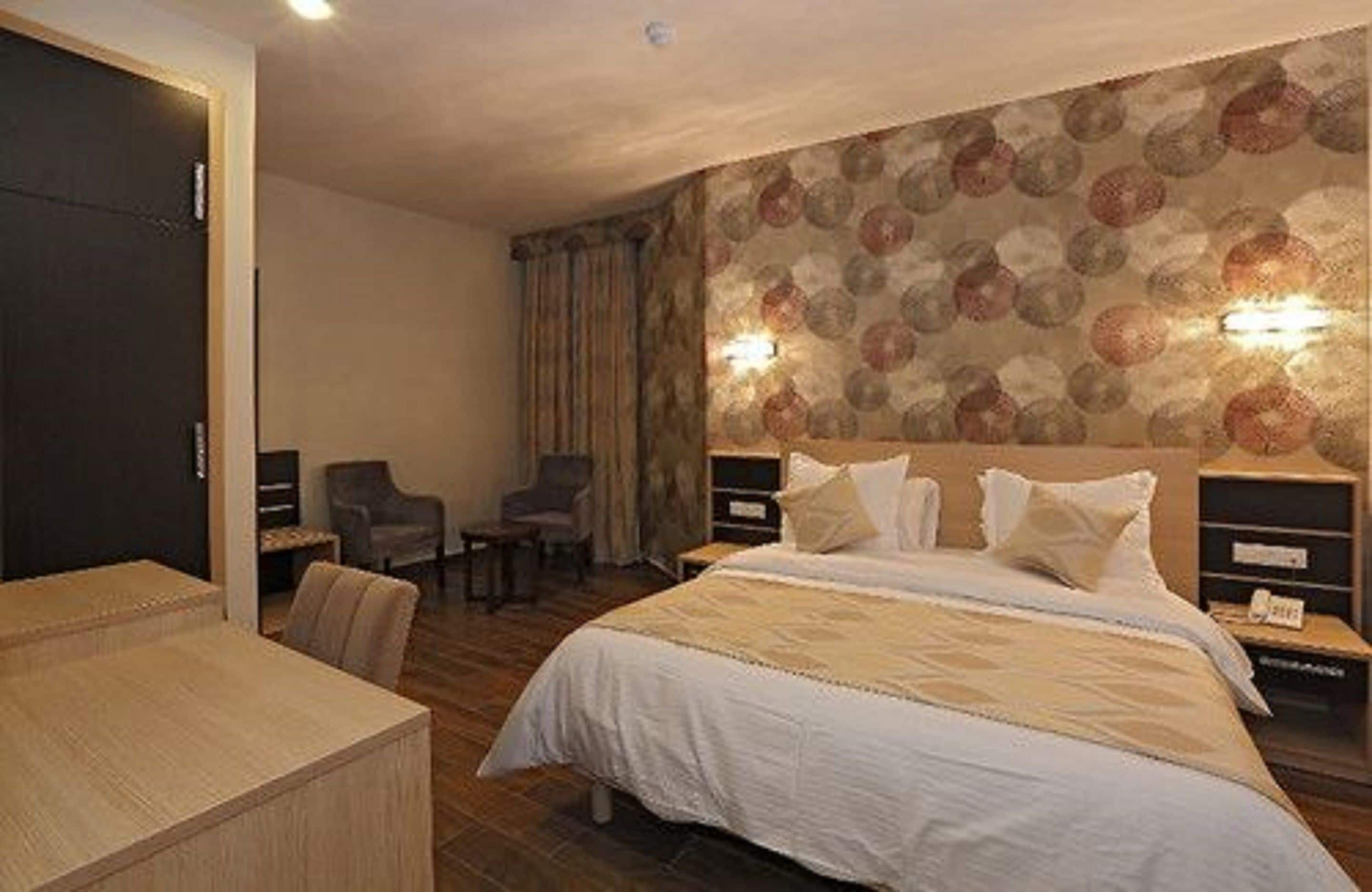 A hotel room with a large bed, two bedside tables, a chair, and a desk.