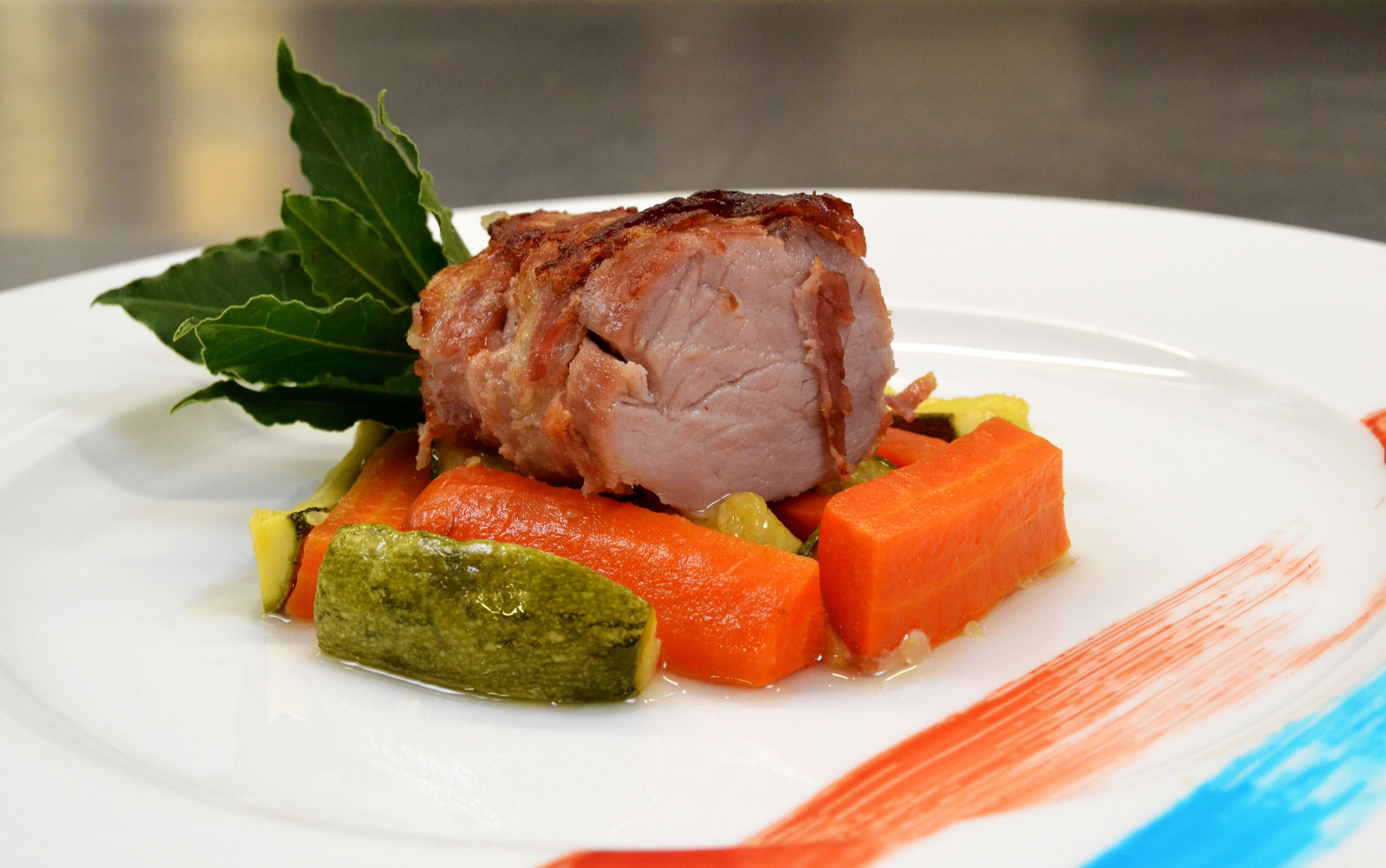 Un plato con carne, zanahorias y un vegetal verde.